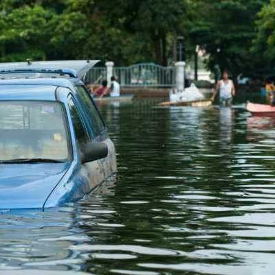 flood-cars pickup truck in flooded road with water up to the door handles and people and row boat in background